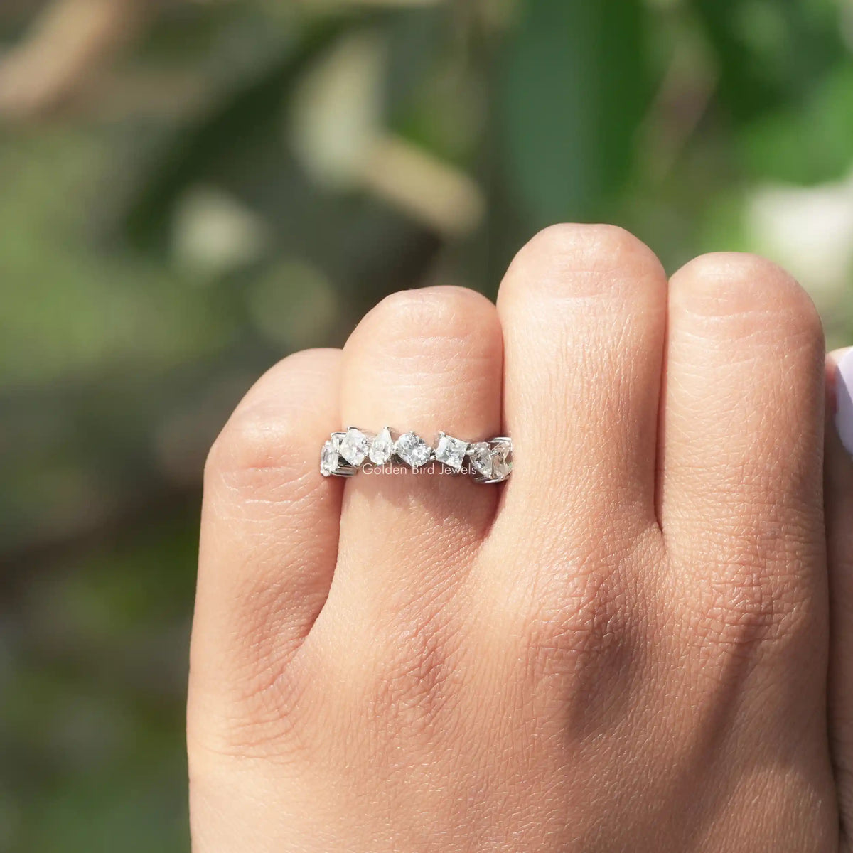 White metal moissanite eternity band on a hand, featuring small faceted stones