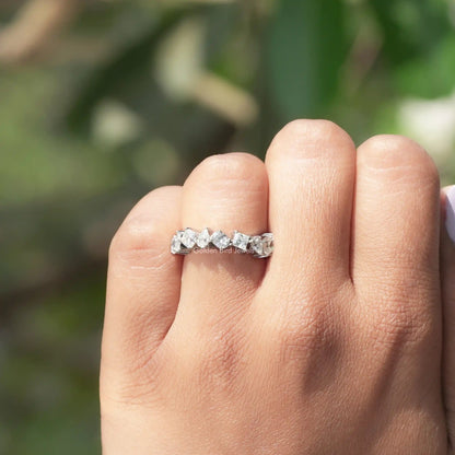 White metal moissanite eternity band on a hand, featuring small faceted stones