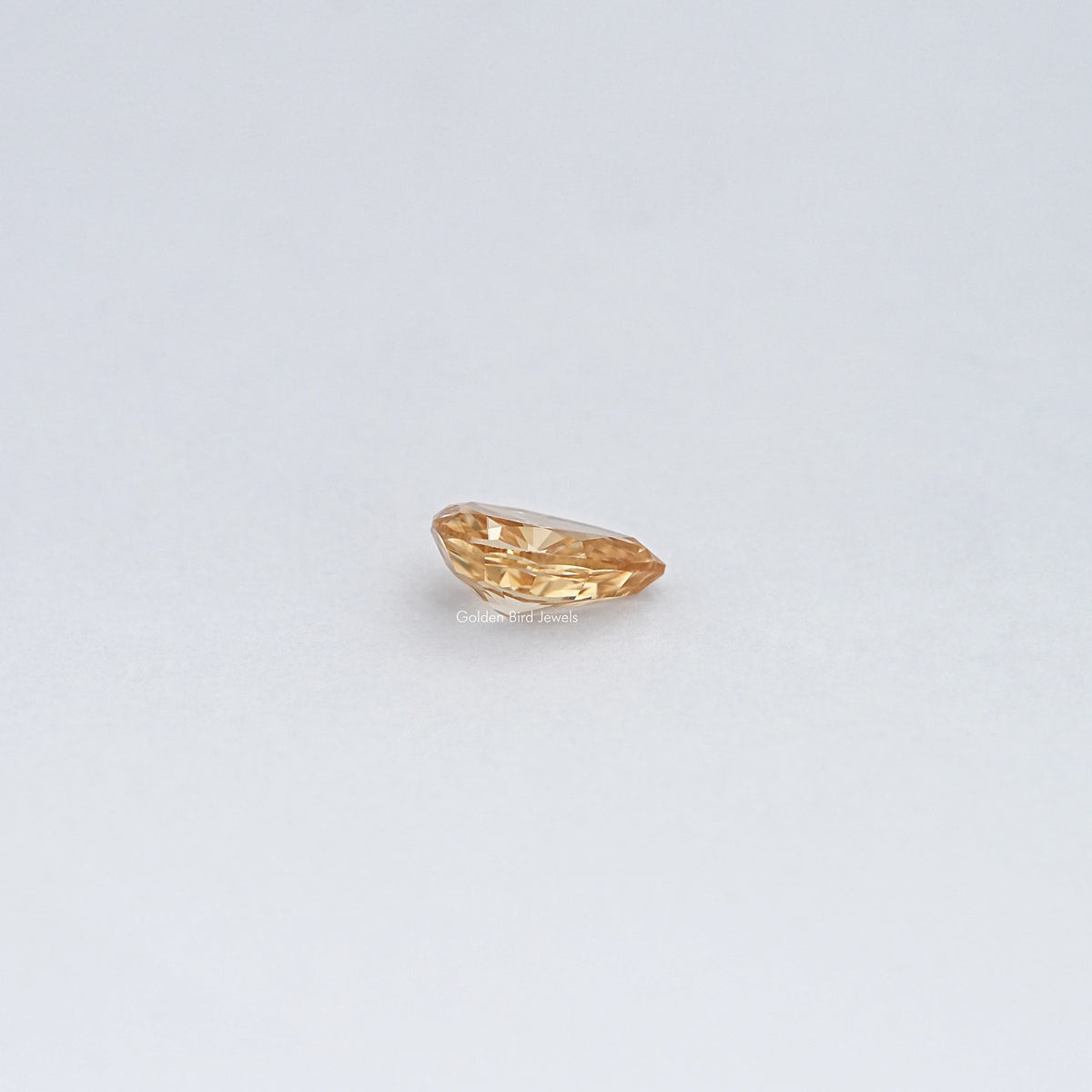 Pear-cut moissanite loose stone, golden champagne tone, horizontal facet view