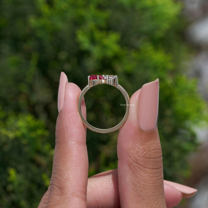 Gold-tone engagement ring featuring a red pear-cut center stone and diamond side sparkle