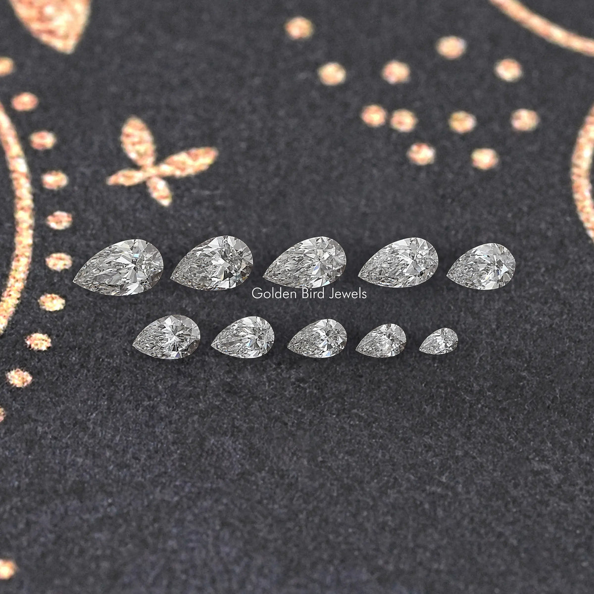 Assorted pear-shaped lab-grown diamonds laid out on dark display