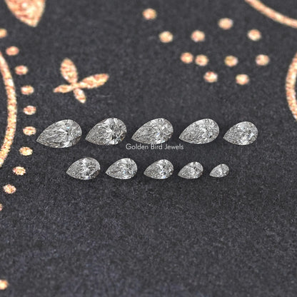 Assorted pear-shaped lab-grown diamonds laid out on dark display