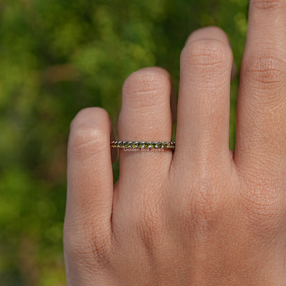 Green-stone eternity band ring with round stones across the top
