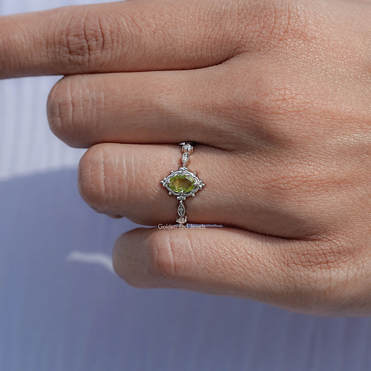 Silver ring with oval peridot-green gemstone and ornate halo setting