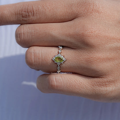 Silver ring with oval peridot-green gemstone and ornate halo setting