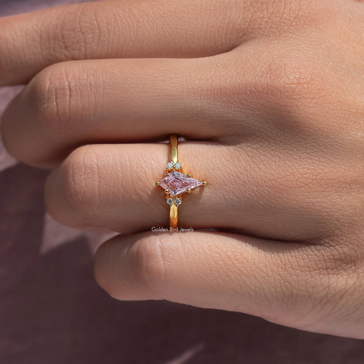 Gold ring with pink kite-cut gemstone centerpiece and small side accents