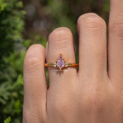 Gold ring with pink kite-cut center stone and three-stone style sparkle