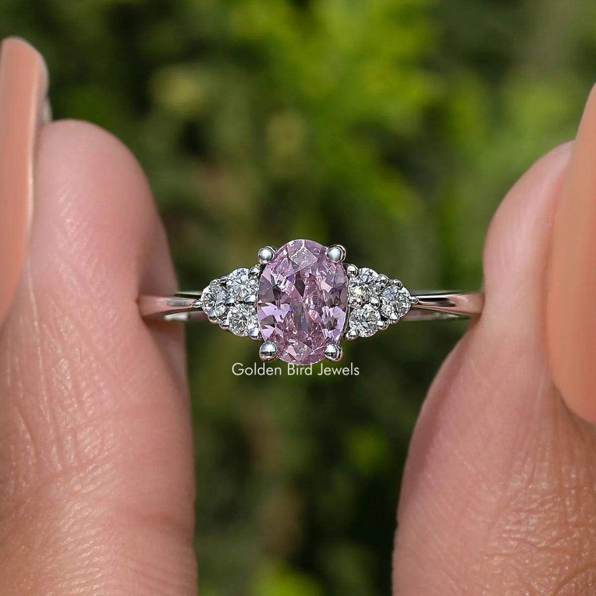 Silver ring with oval pink gemstone center and glittering halo of small stones