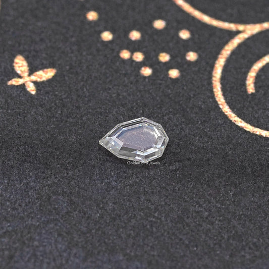 Faceted clear step-cut moissanite loose gemstone on dark fabric background.