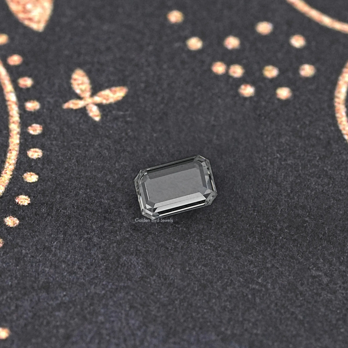 Emerald-cut loose diamond on dark display fabric, clear rectangular center stone