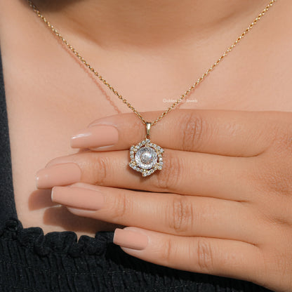 Round moissanite halo pendant on gold-tone chain shown resting across fingers