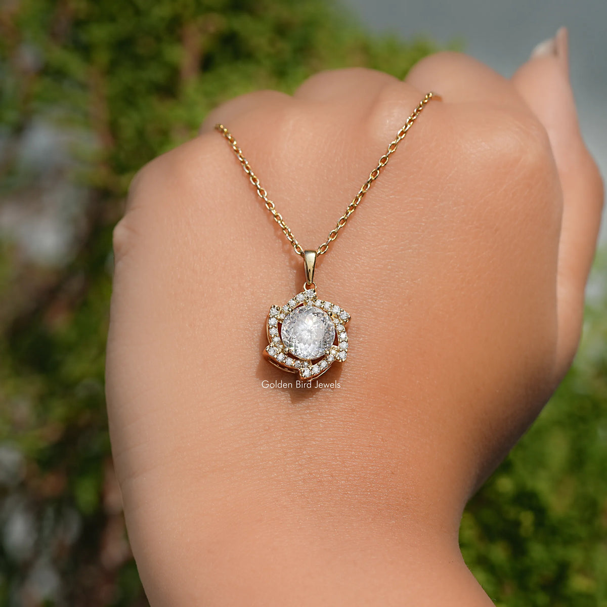 Gold-tone chain with round moissanite halo pendant, resting on open palm