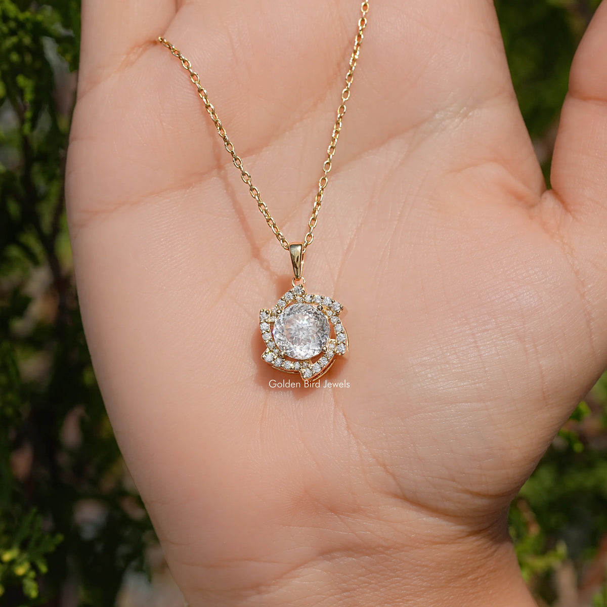Round moissanite halo pendant on a gold-tone chain viewed from the side