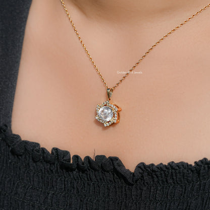 Close view of round moissanite halo pendant on gold-tone chain at collar