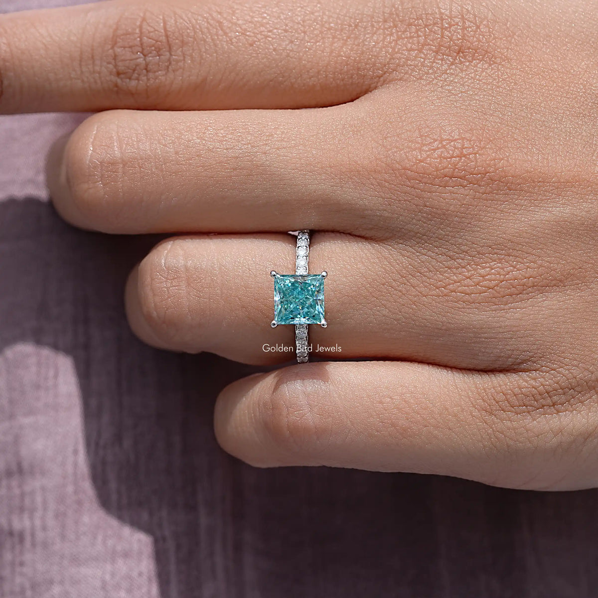 Princess cut moissanite solitaire ring in sterling silver, worn on a finger