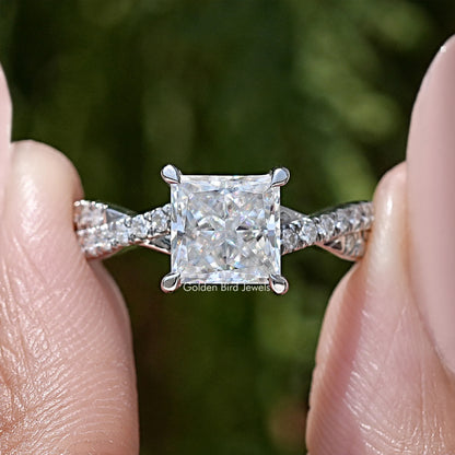 Close-up of twisted accent stones and princess-cut moissanite center in sterling setting
