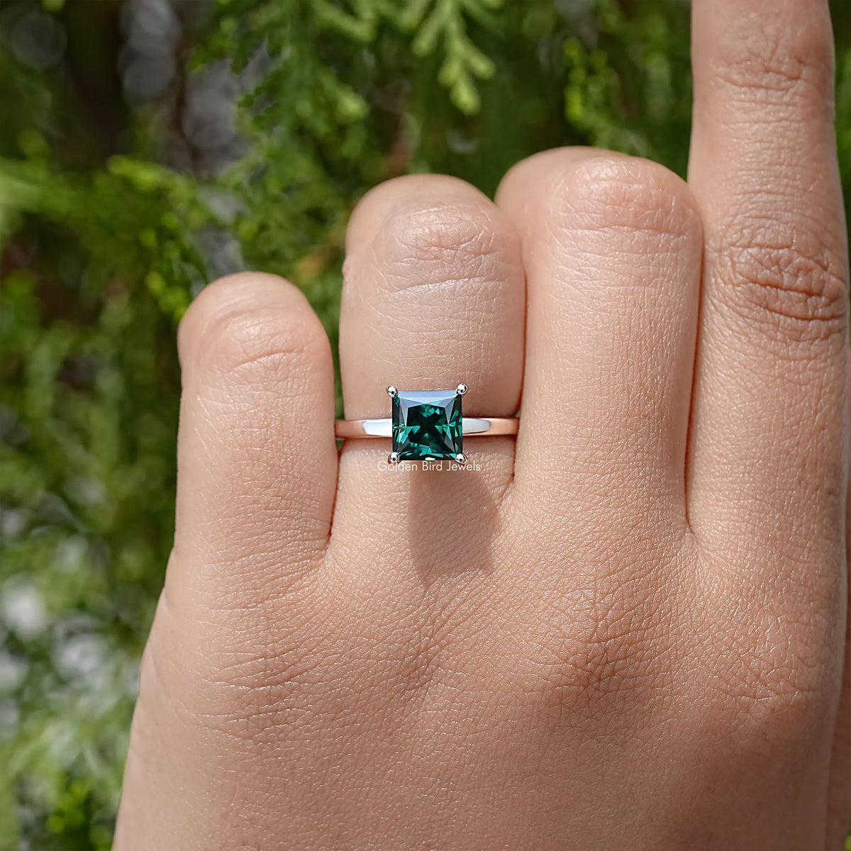 Emerald-green princess-cut moissanite wedding ring with thin silver band and halo detail