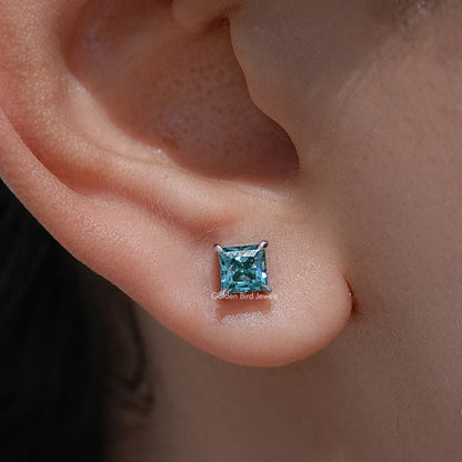 Screw-back stud earrings with blue princess-cut gemstone on visible earlobe