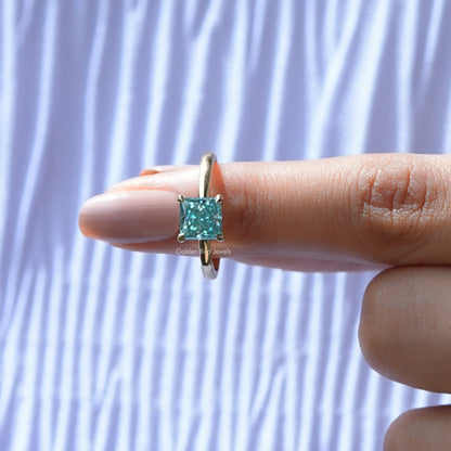 Silver princess-cut solitaire ring on finger, cyan-blue square moissanite centerpiece