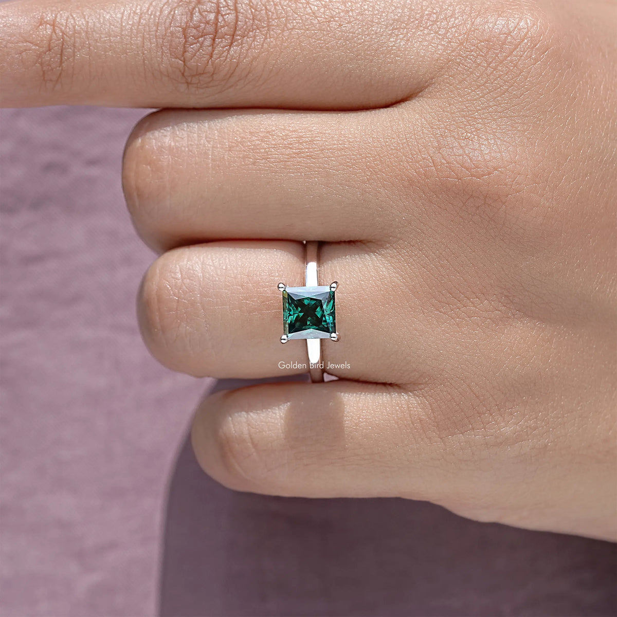 Princess-cut moissanite hidden halo wedding ring with emerald-green center stone on silver band