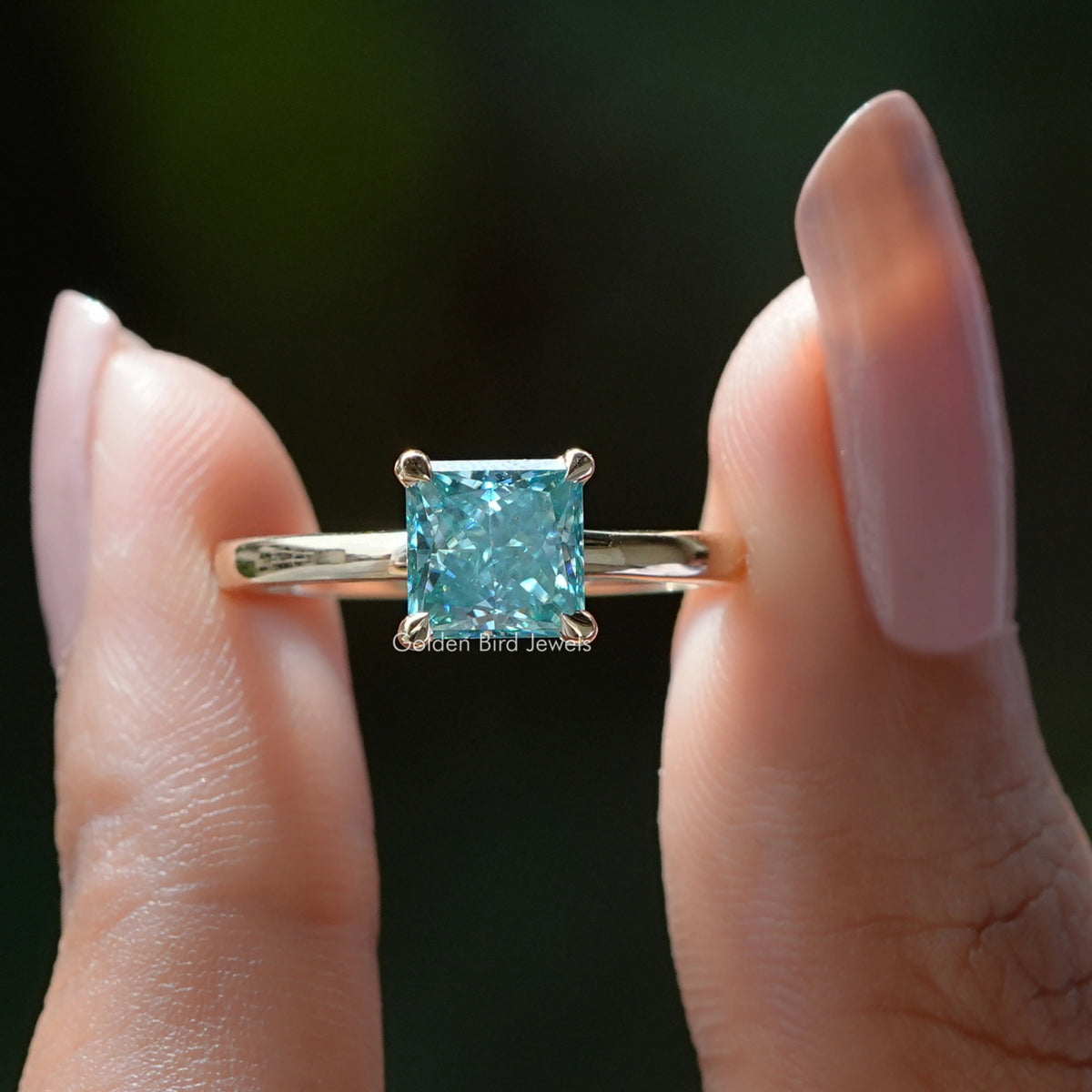Silver princess-cut solitaire ring, cyan-blue square stone and prong setting close-up