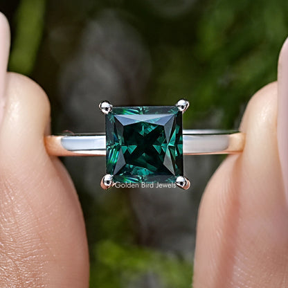 Close-up of princess-cut emerald-green moissanite center with halo on sterling silver ring