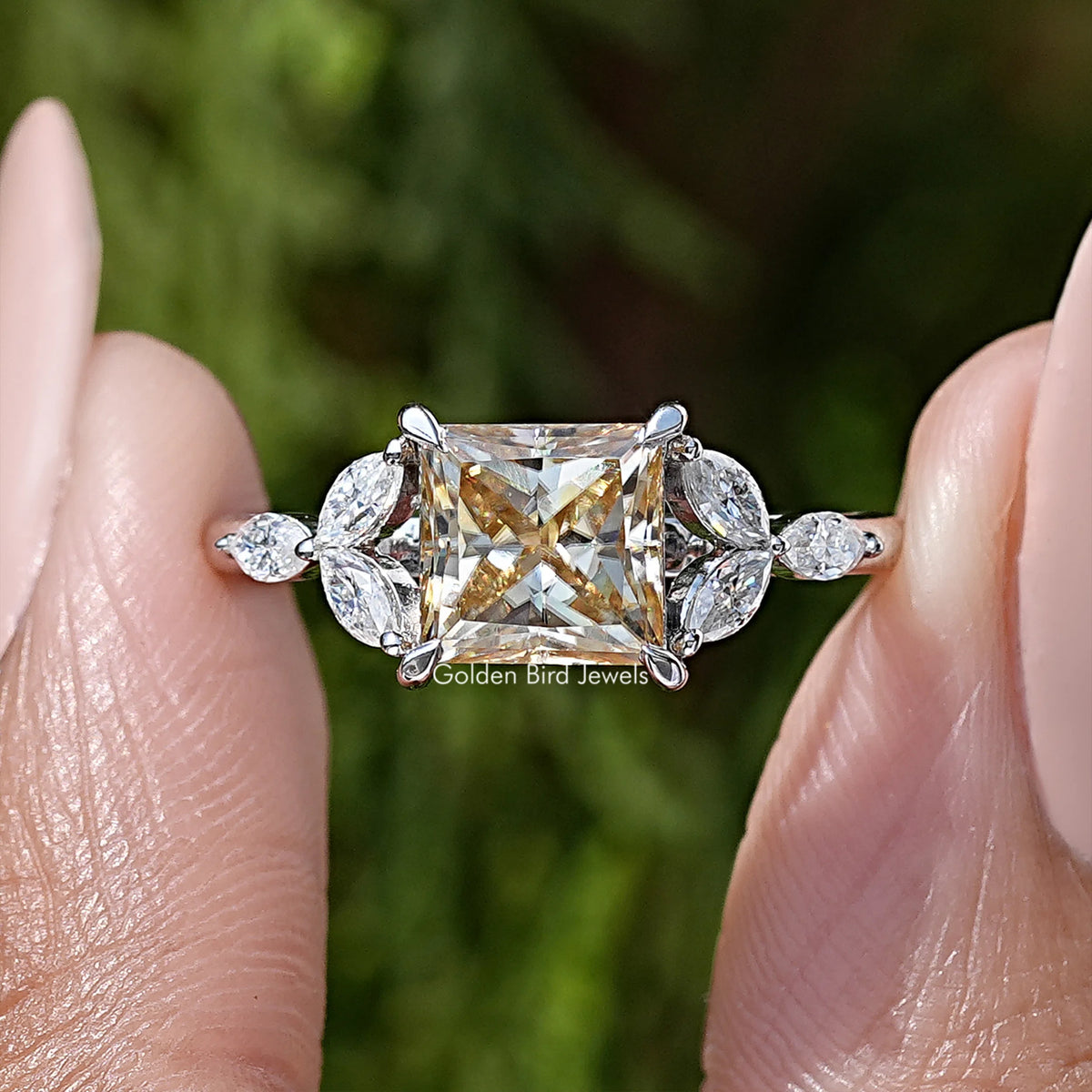Close-up princess-cut moissanite engagement ring with rectangular center stone and round sides