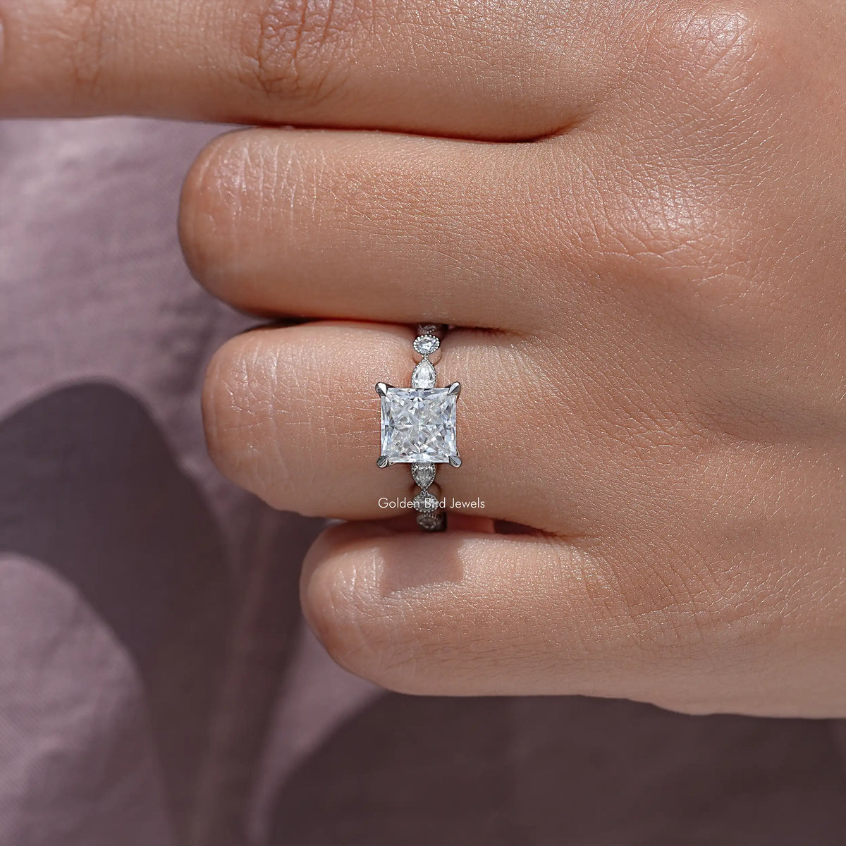 Close-up of sterling silver princess-cut ring with small side stones