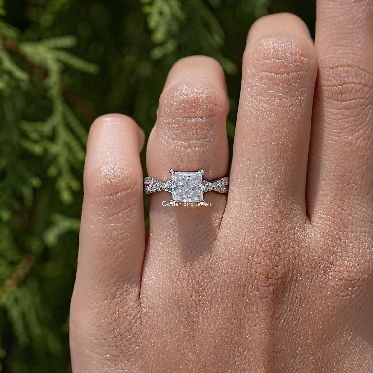 Sterling silver ring on finger featuring princess-cut moissanite and twisted shoulders
