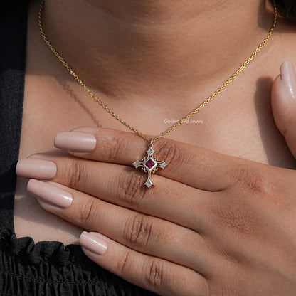 Gold chain cross pendant with square red gemstone and silver side bars, close-up