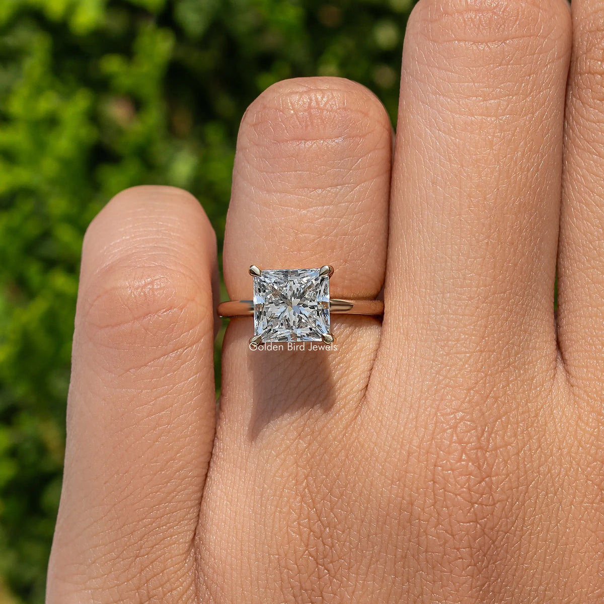 Princess-cut diamond solitaire ring with square center stone on open hand