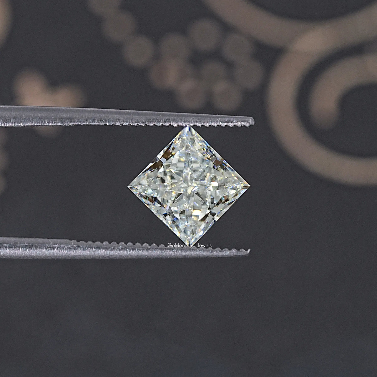 Princess-cut moissanite loose stone, on tweezers; close-up of faceted center.