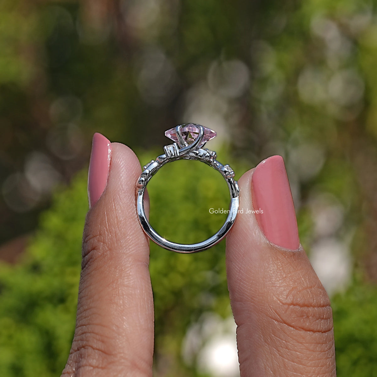 Lab gemstone leaf-style engagement ring shown from side with pink center stone and prongs