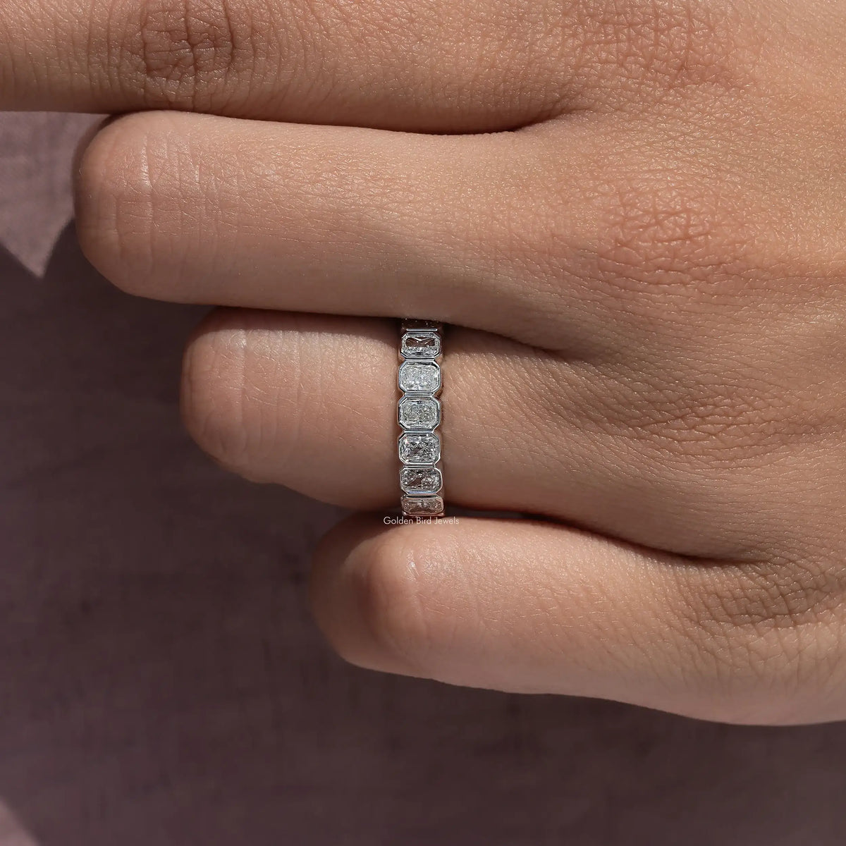 Silver eternity band ring with rectangular bezel-set stones in a vertical row