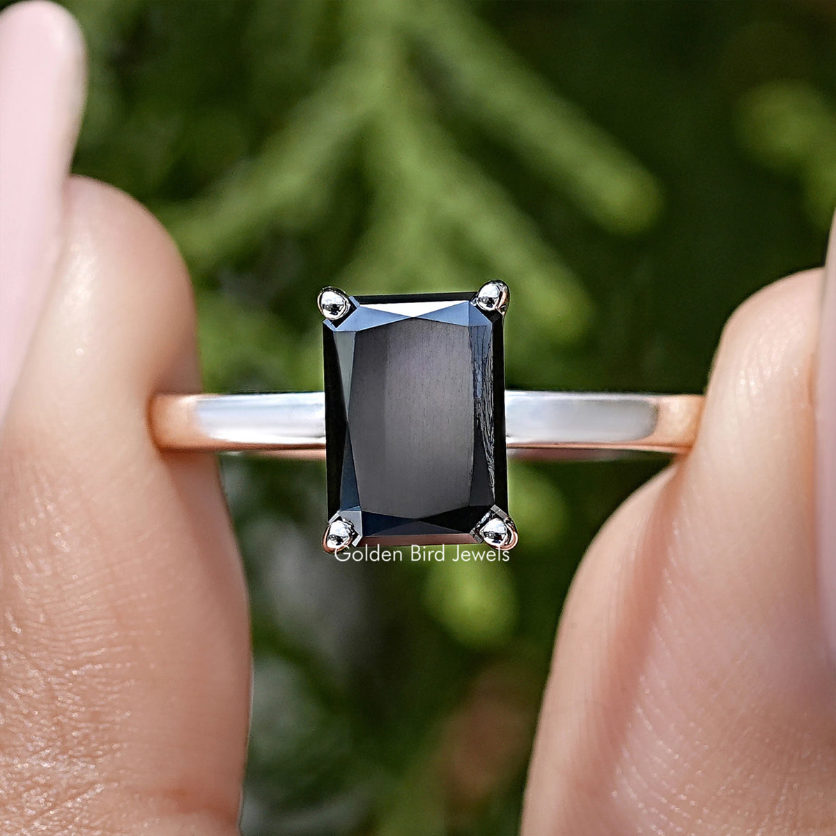 Front view of silver ring with square black radiant-cut center stone and halo prongs
