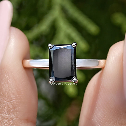 Front view of silver ring with square black radiant-cut center stone and halo prongs