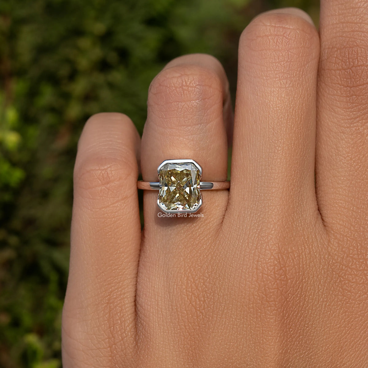 Yellow radiant-cut moissanite solitaire ring in silver, close-up on finger