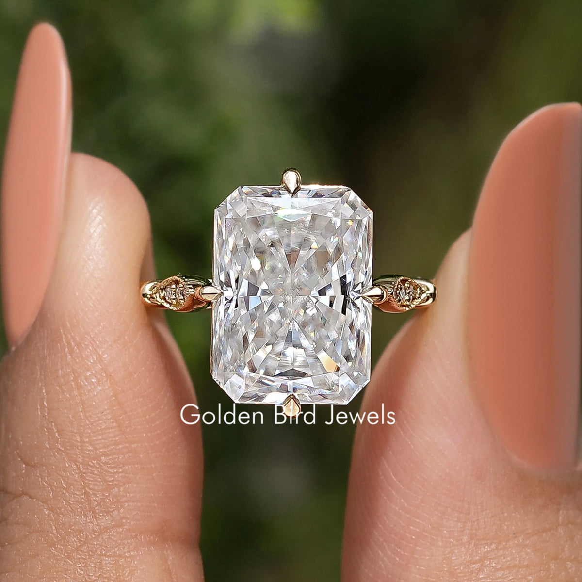 Large rectangular moissanite center stone with gold-toned ribbon side accents