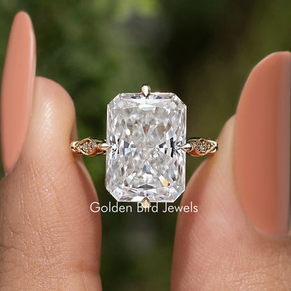 Large rectangular moissanite center stone with gold-toned ribbon side accents