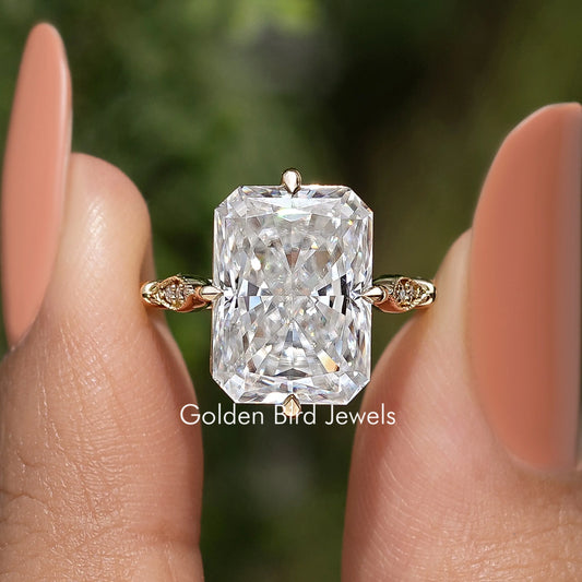 Large rectangular moissanite center stone with gold-toned ribbon side accents