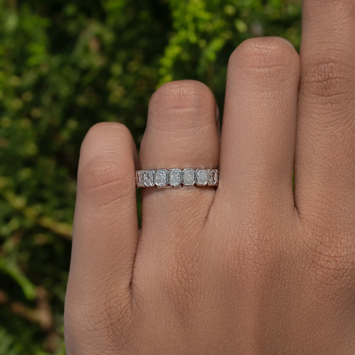 Silver eternity band ring with small bezel-set stones across the top of finger