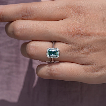 Emerald-cut blue moissanite halo solitaire ring on finger