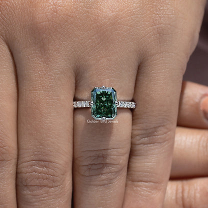 Moissanite solitaire ring showing dark green emerald-cut center and baguette-style side stones