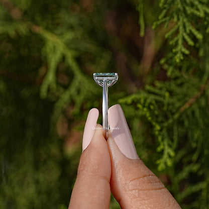 Sterling silver ring with emerald-cut blue-green moissanite and four-prong setting.