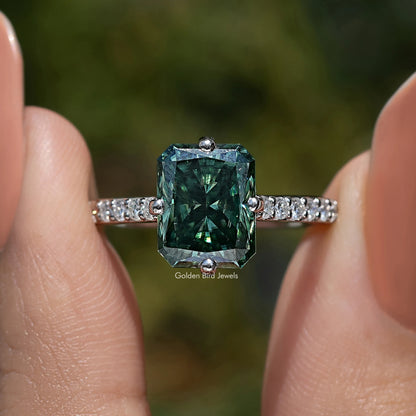 Close-up of dark green emerald-cut moissanite solitaire with diamond side accents