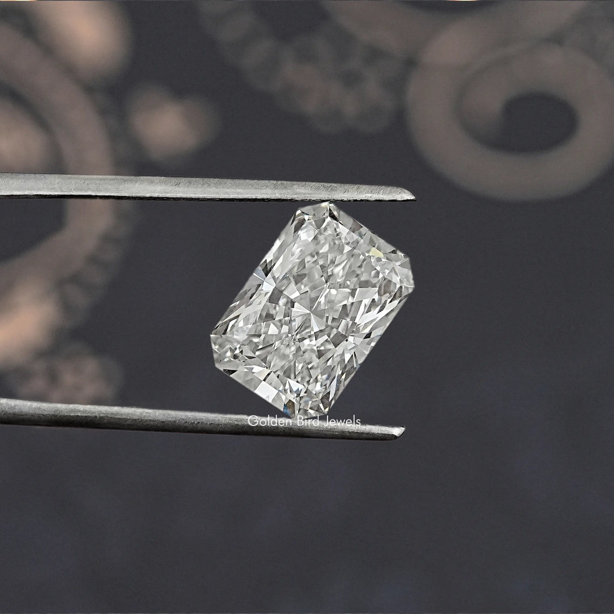 Radiant cut lab-grown diamond held between metal tweezers, close-up