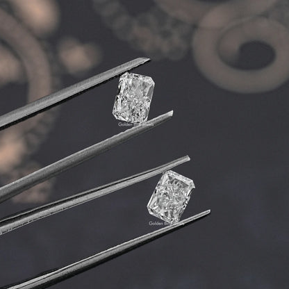 Radiant-cut loose diamonds, two clear stones shown in tweezers from a side angle.