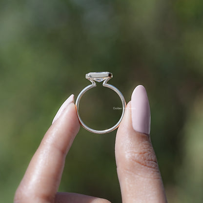 Profile view of gold-toned solitaire ring with radiant-cut stone and half bezel