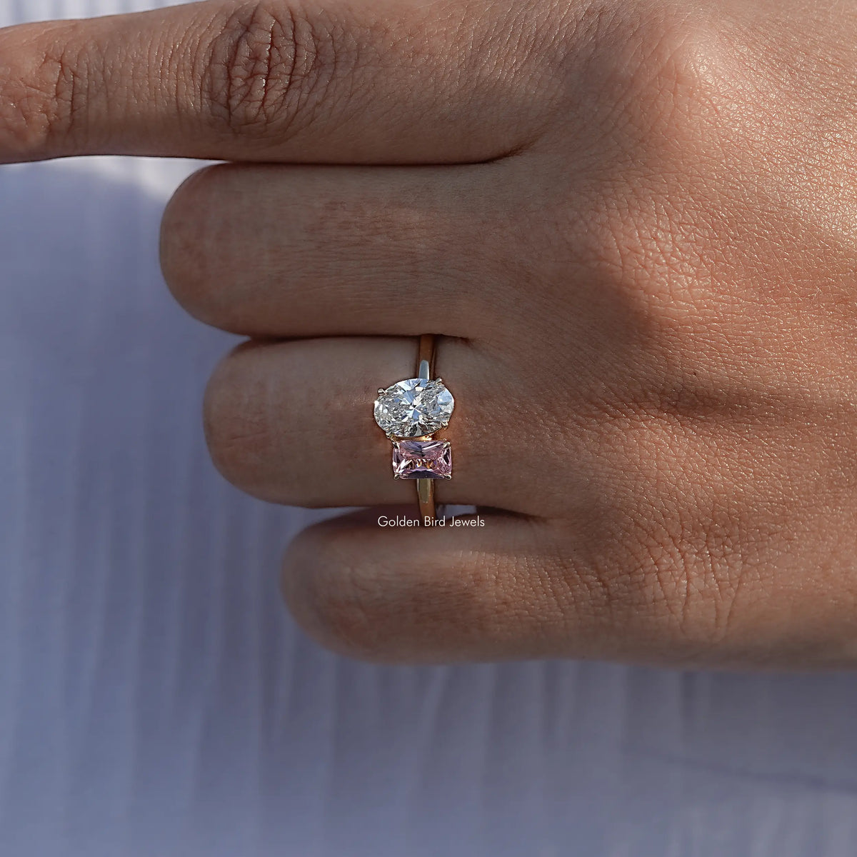Rose gold-tone ring featuring oval white diamond with a pink square gemstone setting
