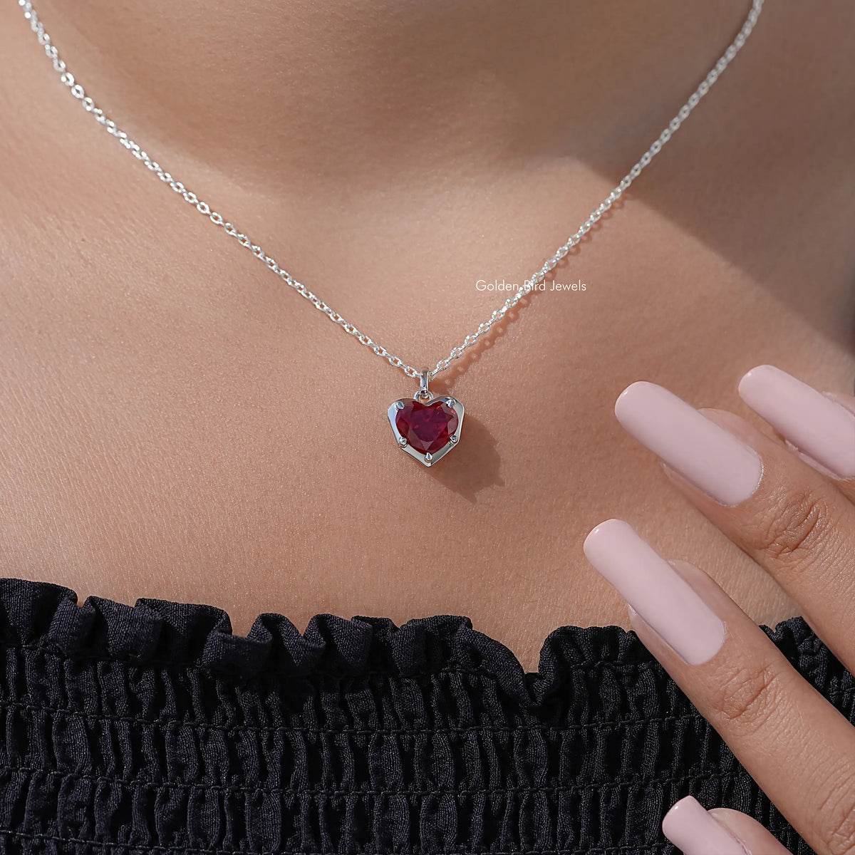Red heart solitaire pendant necklace on silver chain, shown with hand